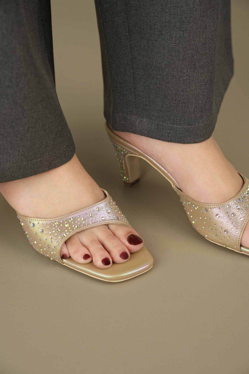 Close-up of feet wearing OPIA 8629 GOLD gold metallic heels with hand-placed stone embellishments and glittery fabric insole
