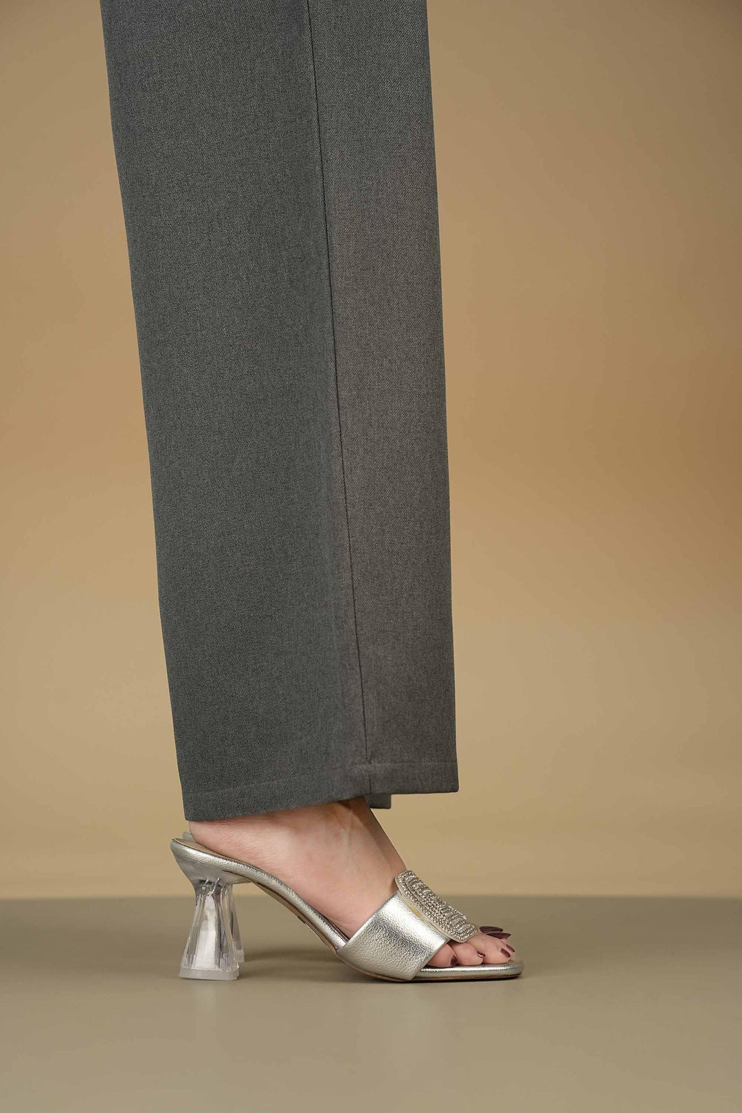 Silver crystal heels with geometric rhinestone design and block heel worn with gray pants