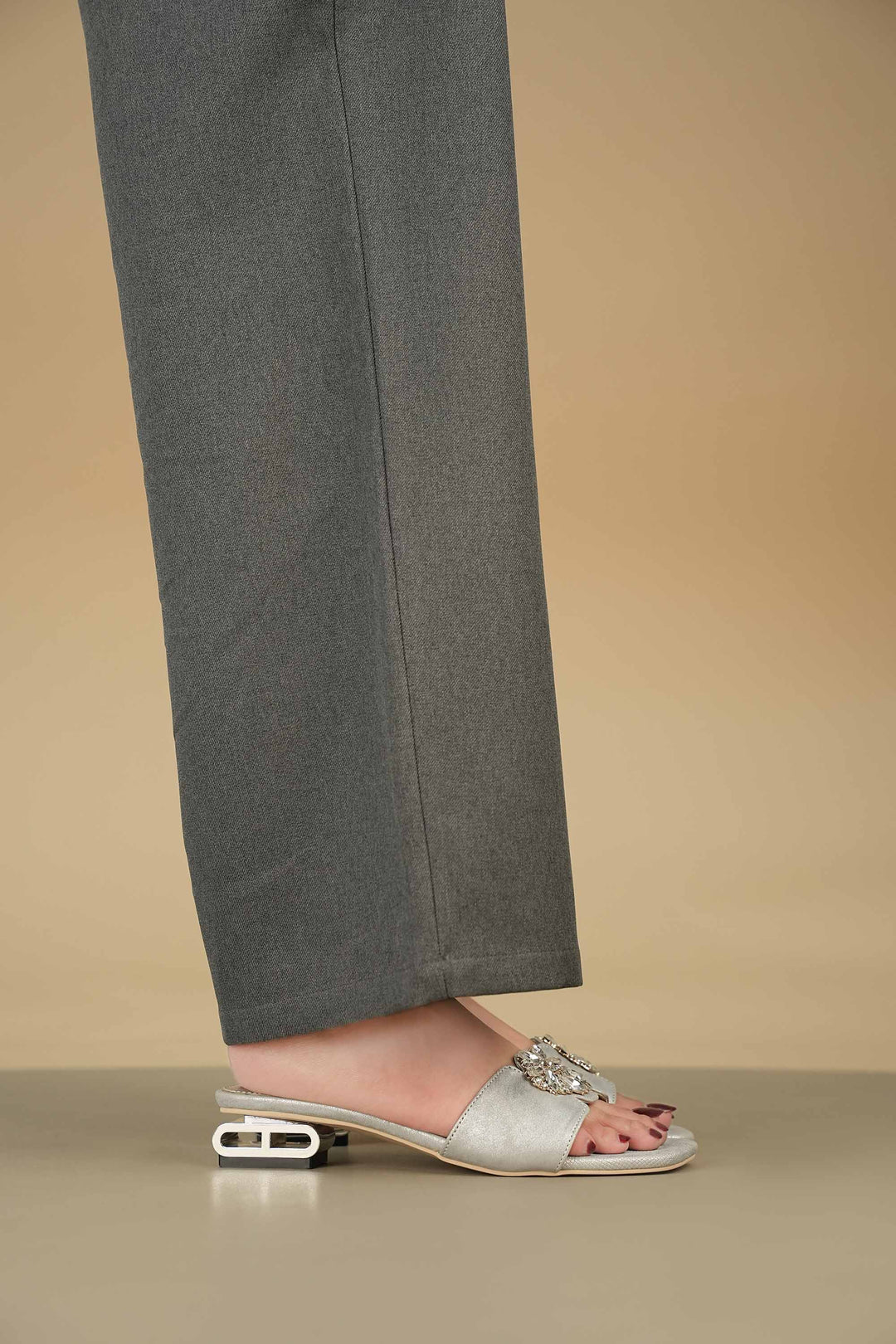 Side view of OPIA 8634 SILVER metallic silver sandal with stone buckle and unique heel design worn with gray pants